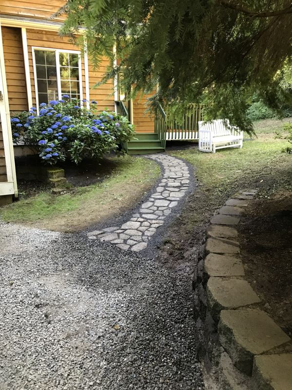 Curving flagstone garden path with stone edging past hydrangeas