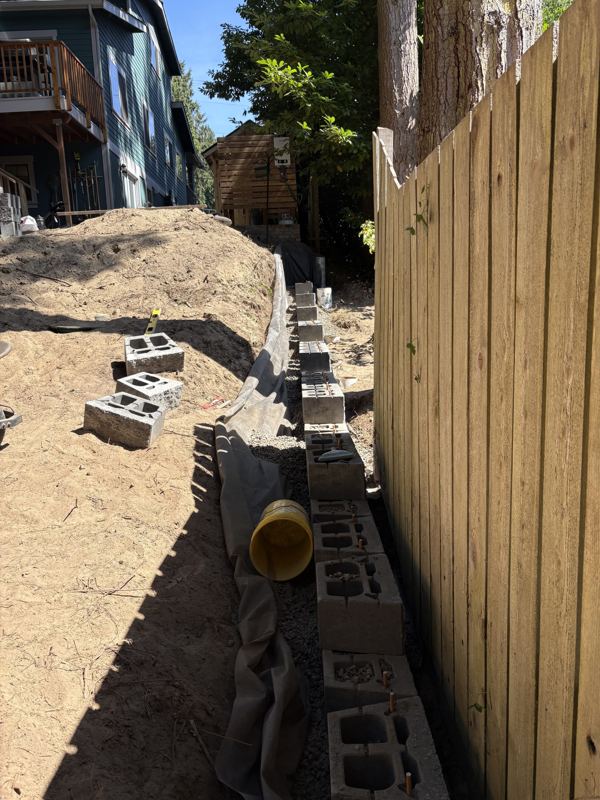 Retaining wall base with drain pipe, gravel and fabric