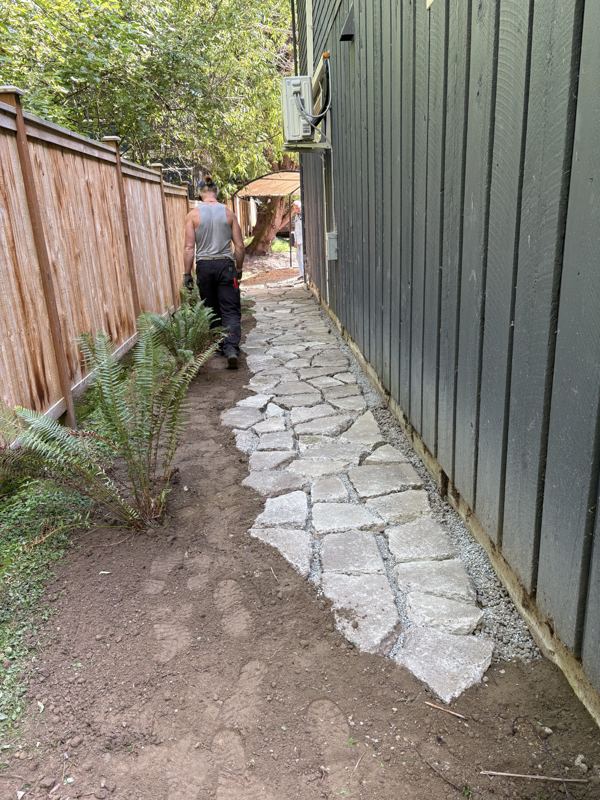 Crew member building a flagstone path along a side yard